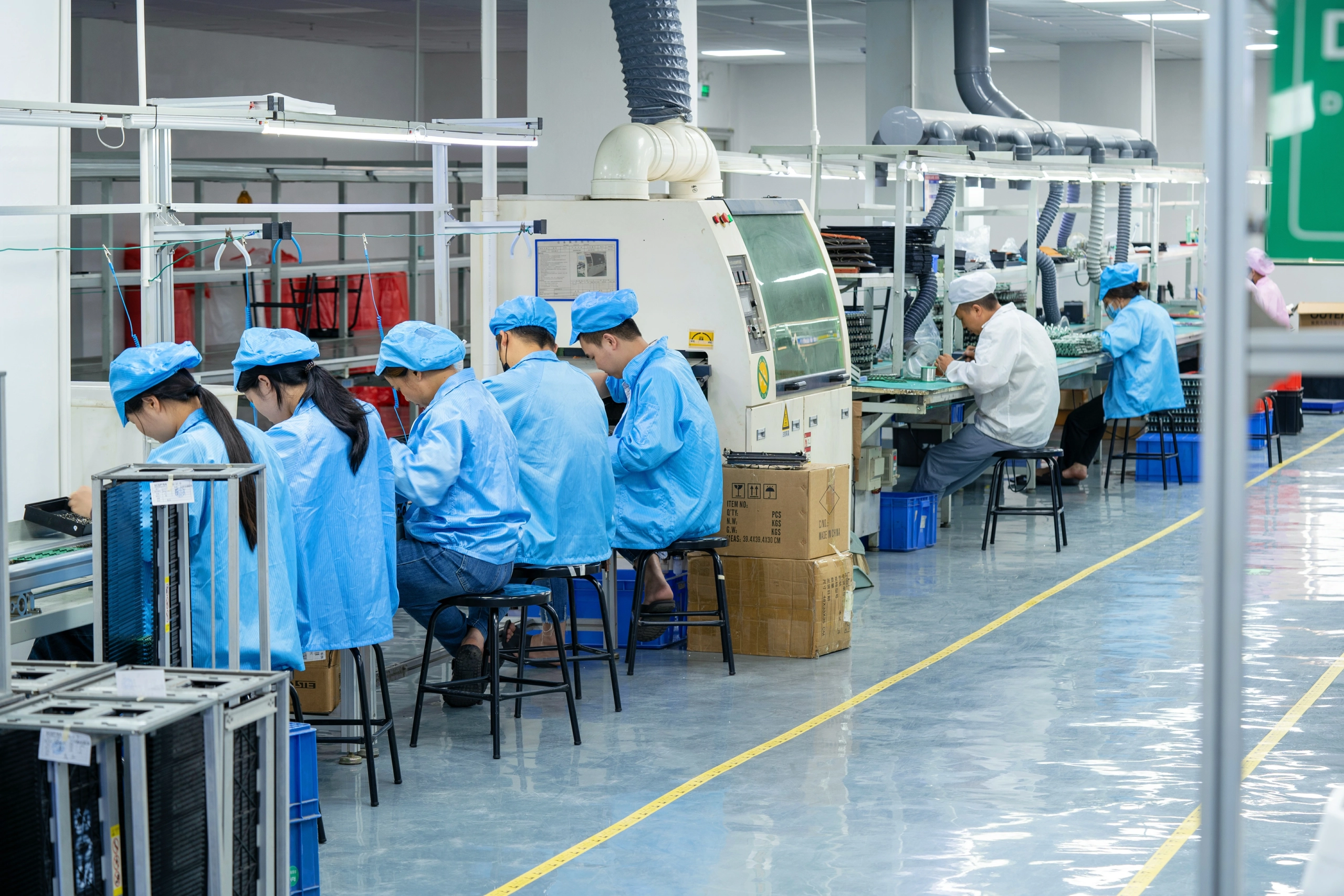Workers wearing electrostatic discharge suits are performing PCB assembly