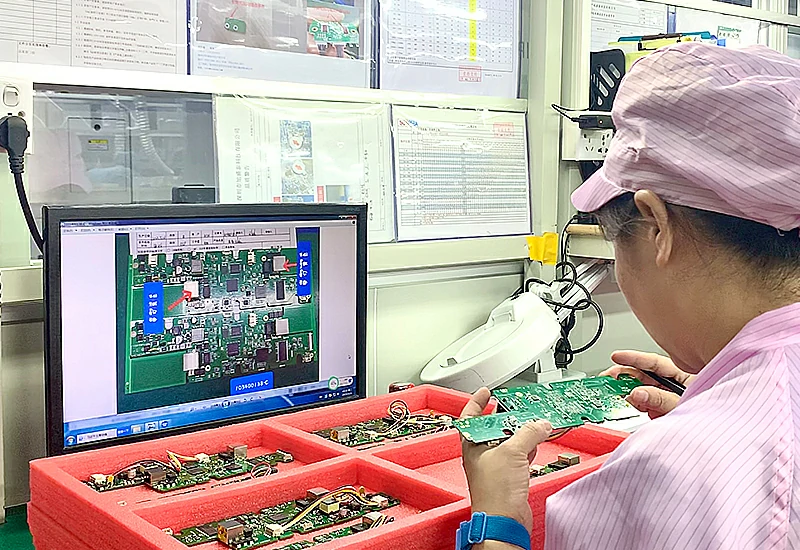 A technician wearing anti-static clothing is checking the assembled PCB