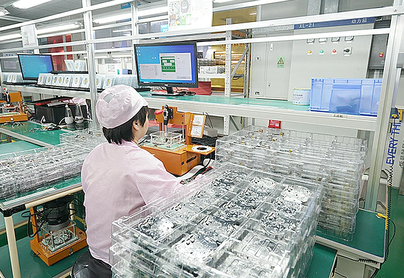 operator wearing an anti-static suit operates a test bench to inspect a circuit board