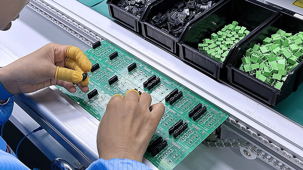 Technicians manually resolder key electronic components onto green automotive PCB assembly